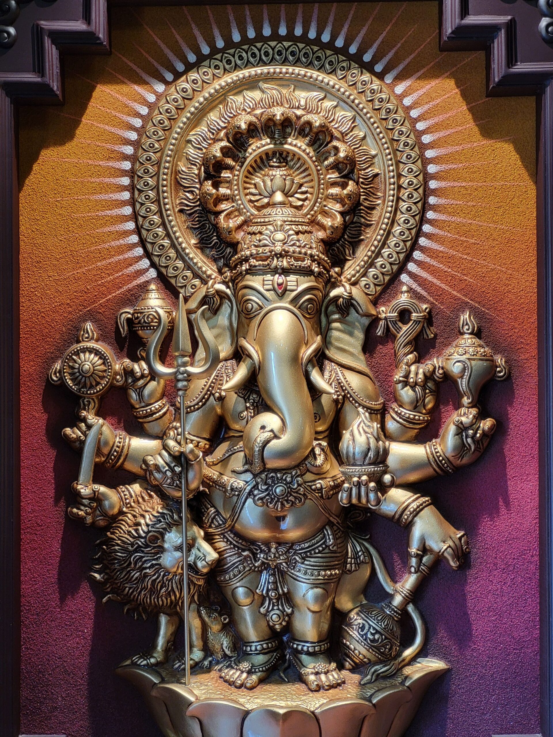 Detailed brass sculpture of Lord Ganesha with multiple arms and intricate design elements.